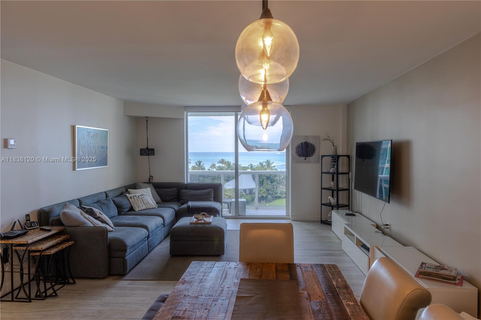 A living and dining area features a sectional sofa, wooden table, and ocean view balcony — 10275 Collins Ave # 634, Bal Harbour FL 33154, BAL HARBOUR, FL