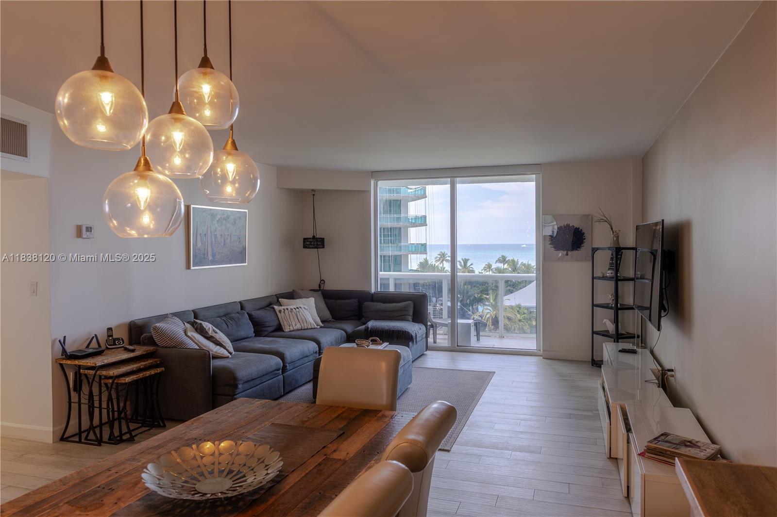 A living and dining area features a sectional sofa, wooden table, and ocean view balcony — 10275 Collins Ave # 634, Bal Harbour FL 33154, BAL HARBOUR, FL
