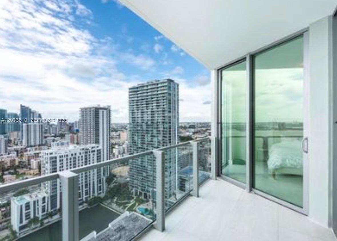 A high-rise balcony with glass railings overlooks a dense urban cityscape with multiple skyscrapers — 2900 NE 7th Ave # 2908, Miami FL 33137, MIAMI, FL