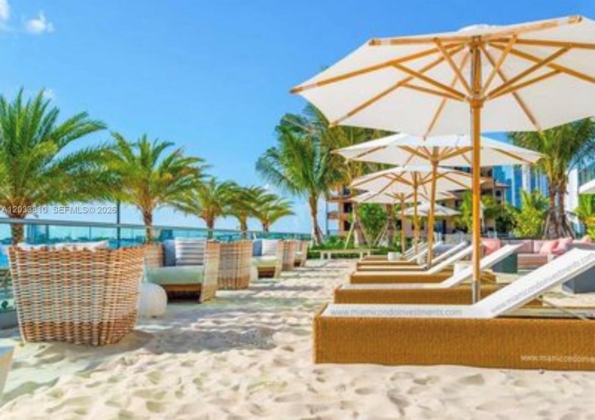 A sandy outdoor terrace features lounge chairs under umbrellas and palm trees — 2900 NE 7th Ave # 2908, Miami FL 33137, MIAMI, FL
