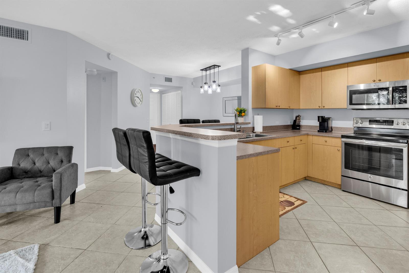 A kitchen with light wood cabinets, stainless steel appliances, and a breakfast bar with stools — 214 Villa Circle # 214, Boynton Beach FL 33435, BOYNTON BEACH, FL