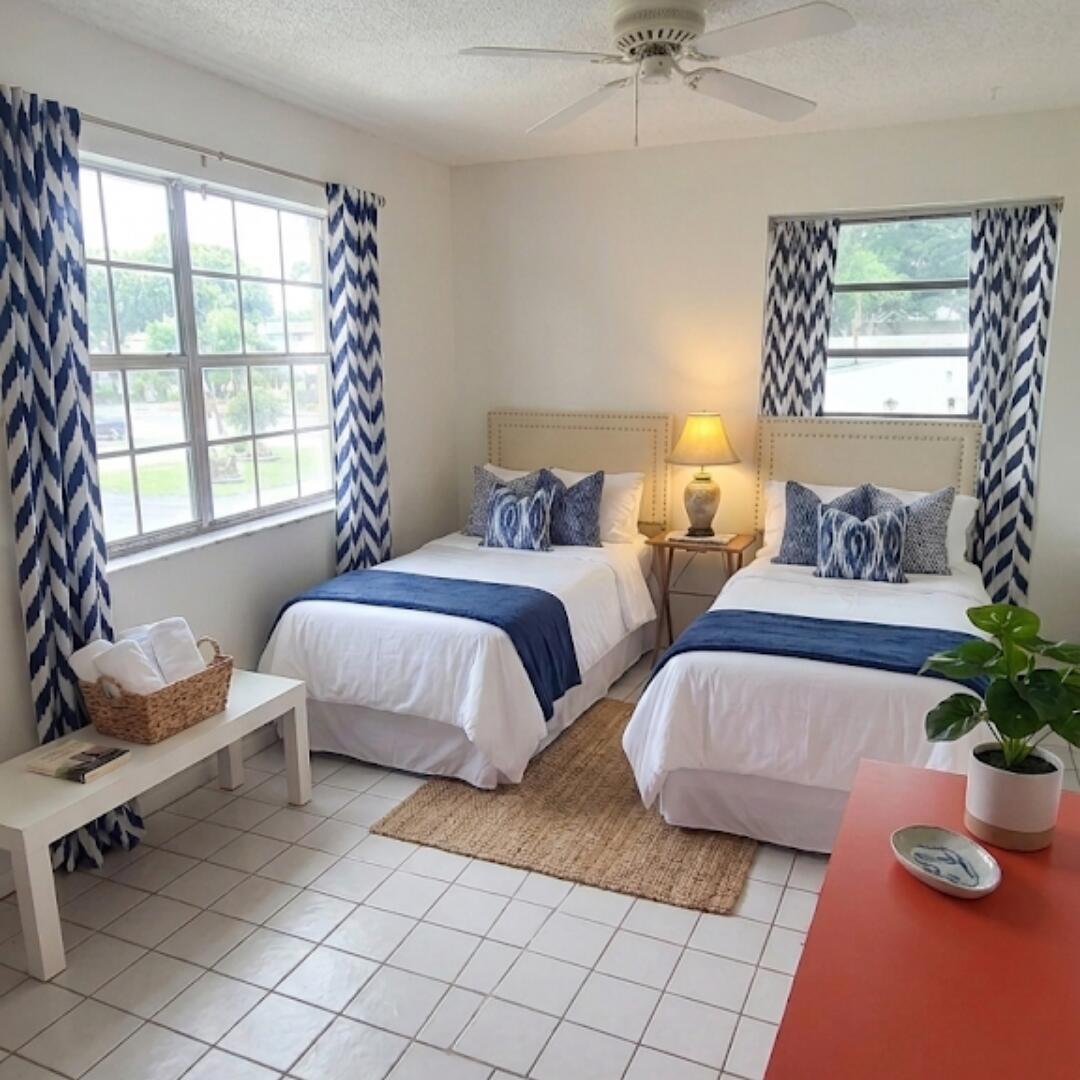 A bedroom features two twin beds, blue chevron curtains, white tile floors, and a ceiling fan — 13746 Via Flora, Delray Beach FL 33484, DELRAY BEACH, FL