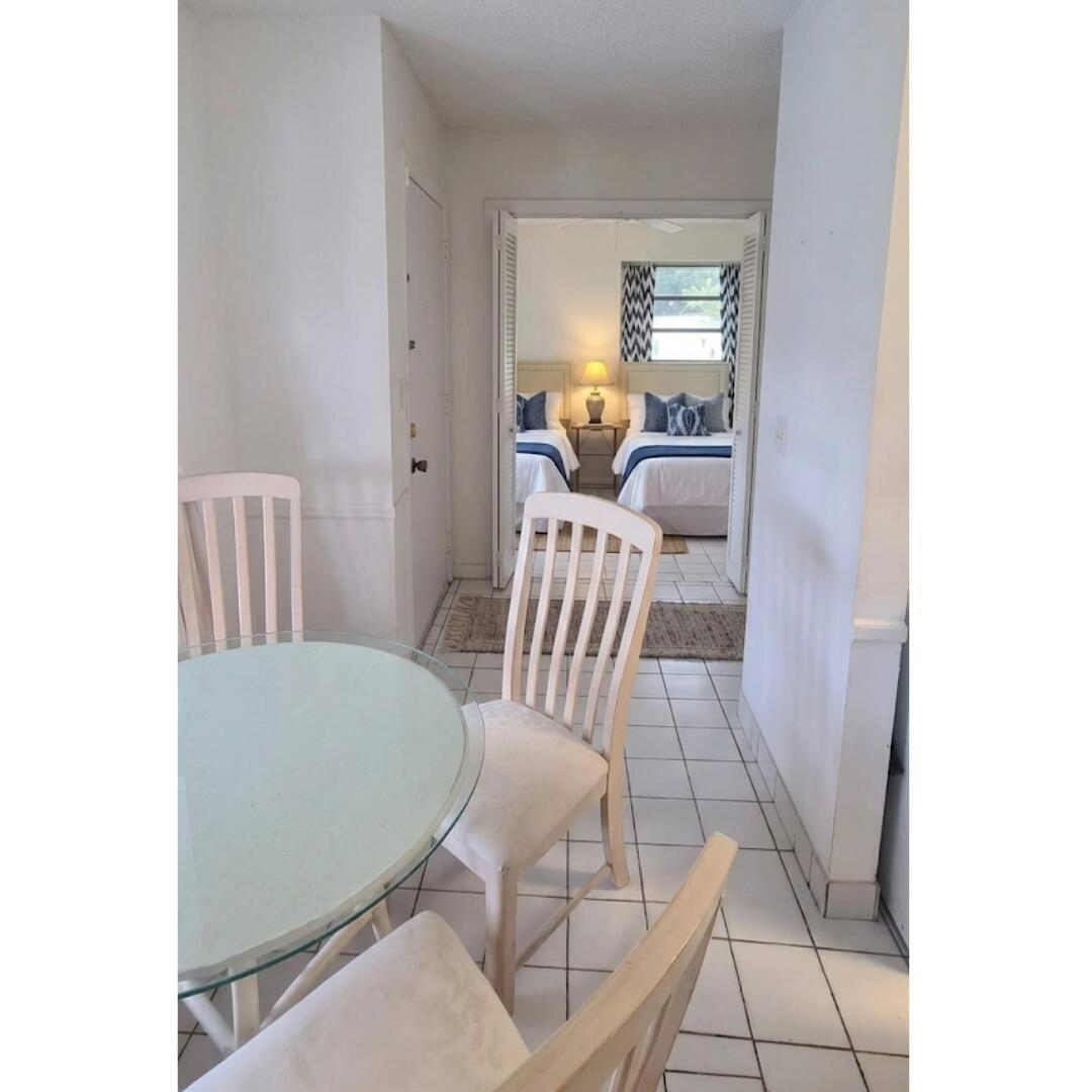A dining area with a glass table leads into a bedroom with two twin beds — 13746 Via Flora, Delray Beach FL 33484, DELRAY BEACH, FL