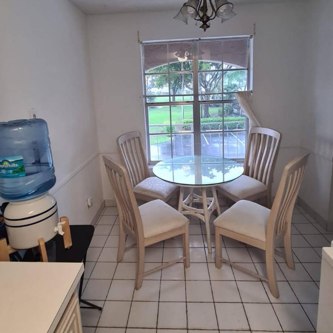 A dining area with a glass-topped table, four chairs, white tile floors, and a window — 13746 Via Flora, Delray Beach FL 33484, DELRAY BEACH, FL