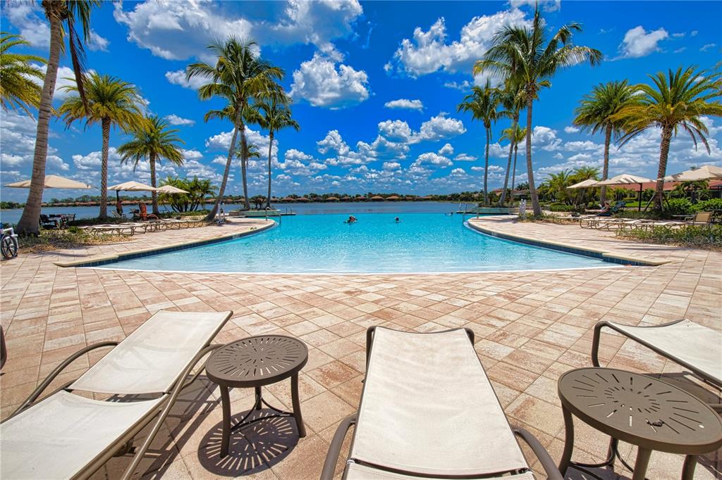 A swimming pool overlooks a lake surrounded by palm trees and lounge chairs on a patio — 104 VILLORESI BOULEVARD, NOKOMIS, FL