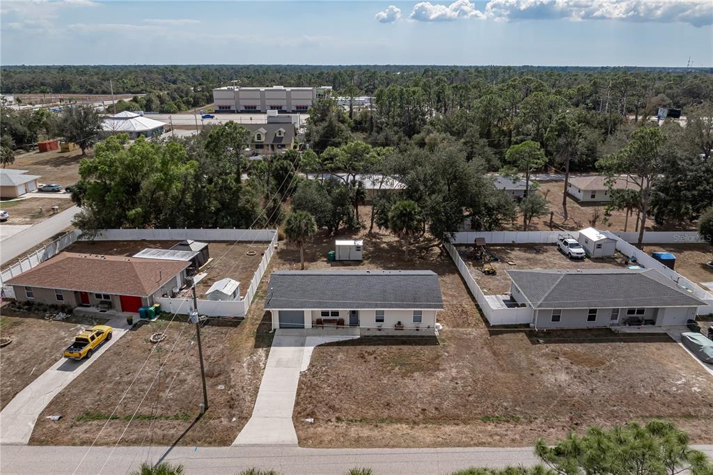 An aerial view shows three single-story houses with driveways and fenced backyards in a suburban area — 17235 URSULA AVENUE, PORT CHARLOTTE, FL