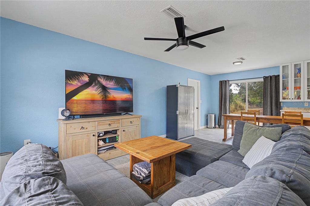 A living room with blue walls, a grey sectional sofa, and a wooden coffee table — 17235 URSULA AVENUE, PORT CHARLOTTE, FL