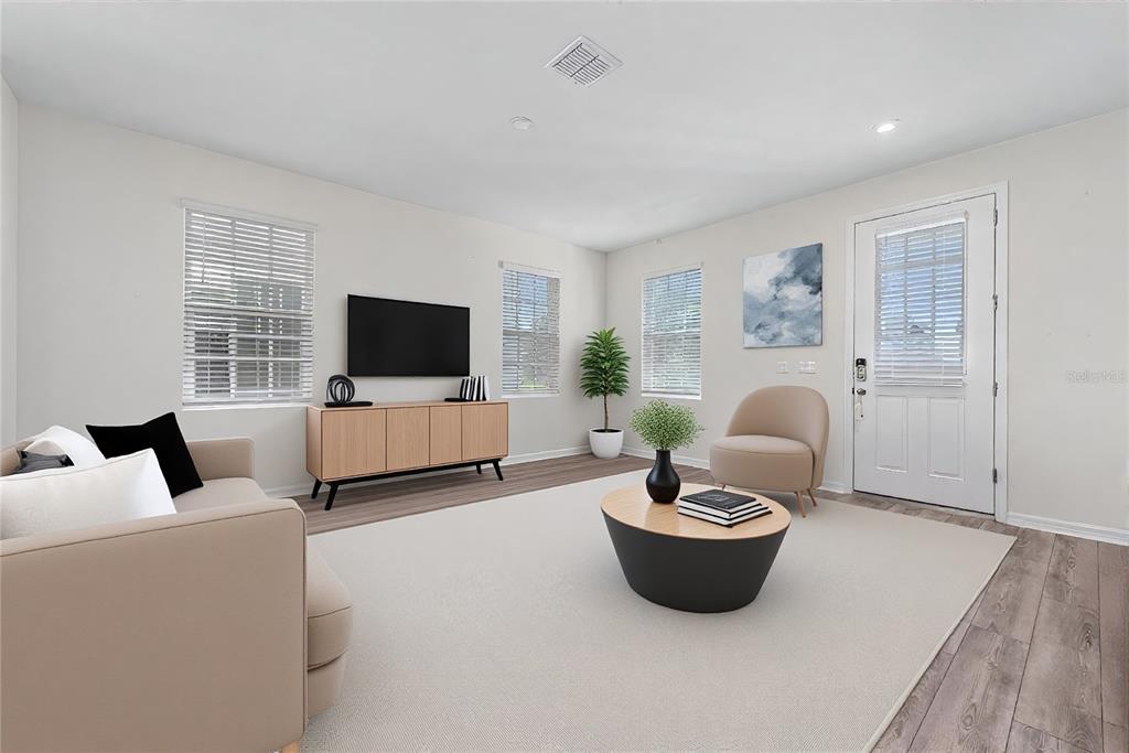 This living room features light walls, wood-look flooring, a beige sofa, and a television console — 2101 CELEBRATION BOULEVARD, KISSIMMEE, FL
