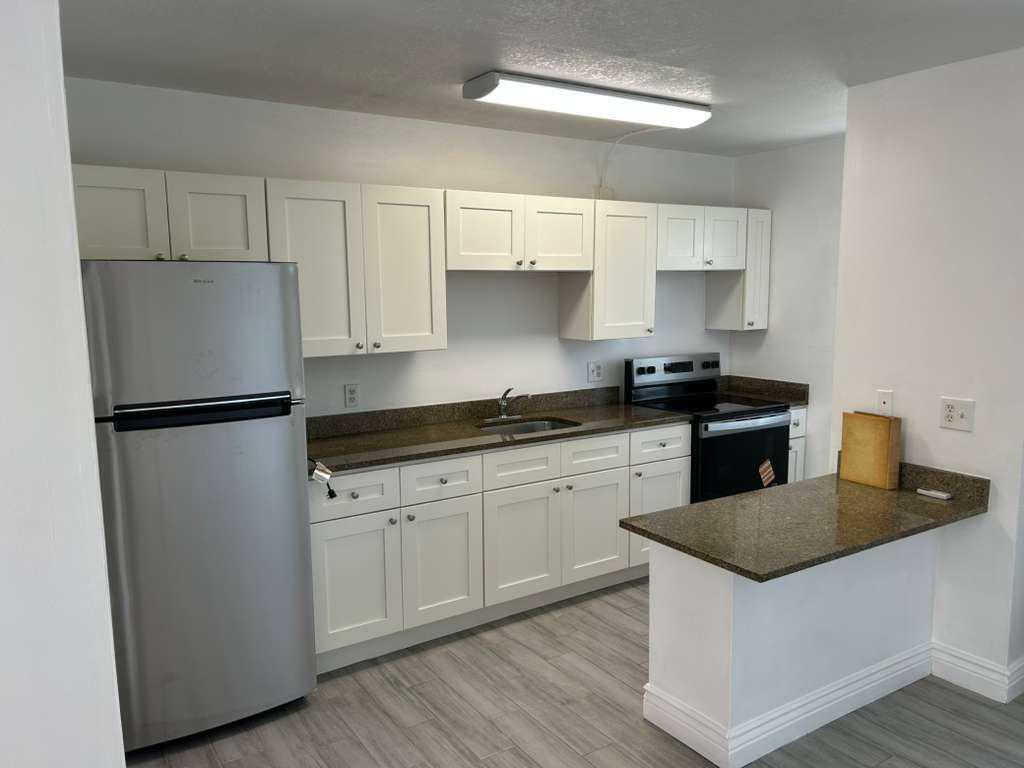 A kitchen with white cabinets, stainless steel appliances, and brown granite countertops — 1081 SE Monterey Road # 12, Stuart FL 34994, STUART, FL