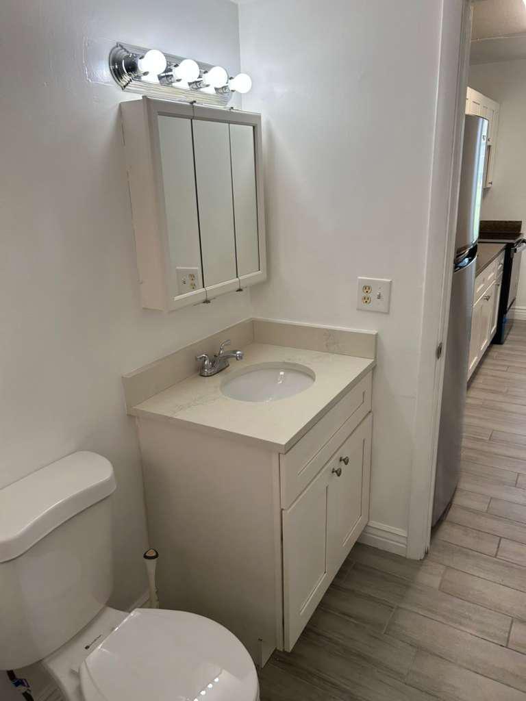 A bathroom with a white vanity, quartz countertop, medicine cabinet, and light-colored tile flooring — 1081 SE Monterey Road # 12, Stuart FL 34994, STUART, FL