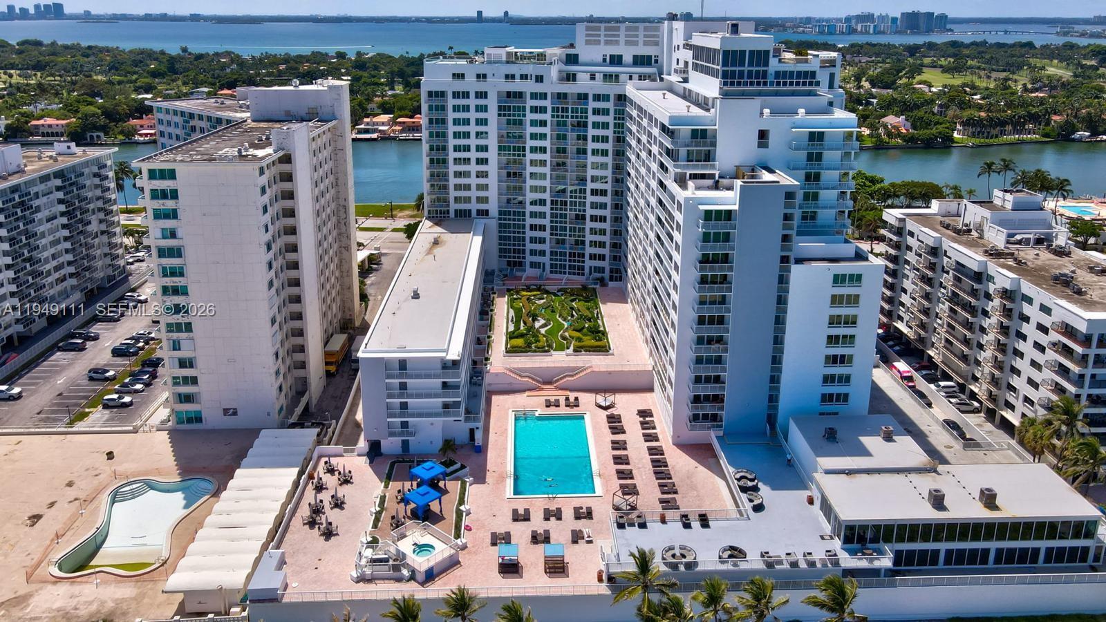 An aerial view shows a high-rise apartment complex with a swimming pool and landscaped courtyard — 5401 Collins Ave # 340, Miami Beach FL 33140, MIAMI BEACH, FL
