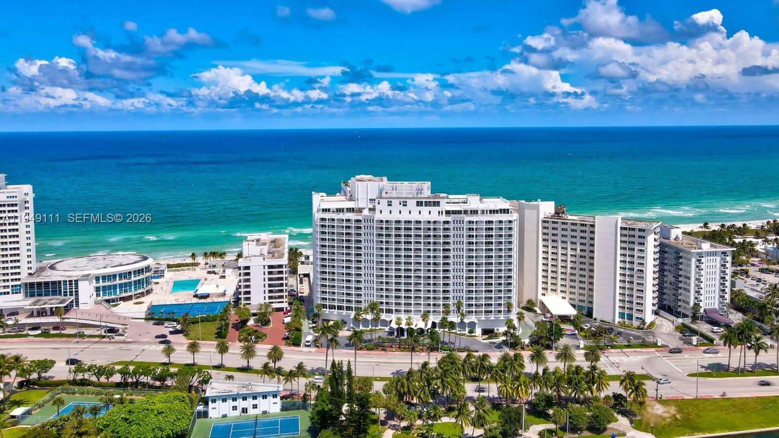 An aerial view shows several high-rise residential buildings situated along a sandy beach and ocean — 5401 Collins Ave # 340, Miami Beach FL 33140, MIAMI BEACH, FL