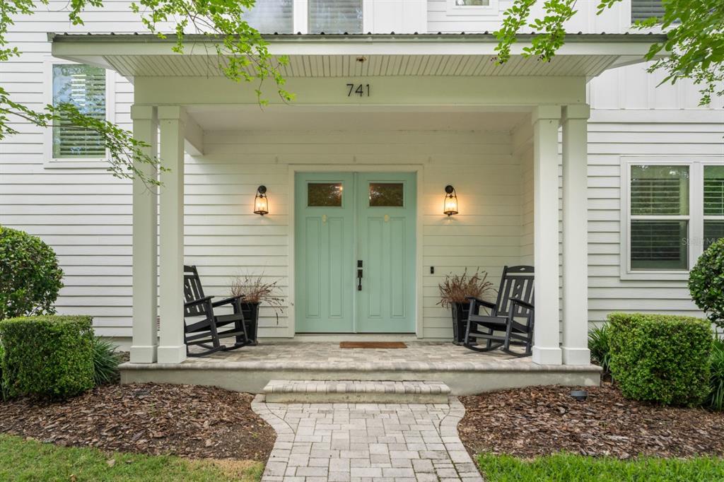 A front porch with a light blue double door, two rocking chairs, and stone steps — 741 SW 133RD WAY, NEWBERRY, FL