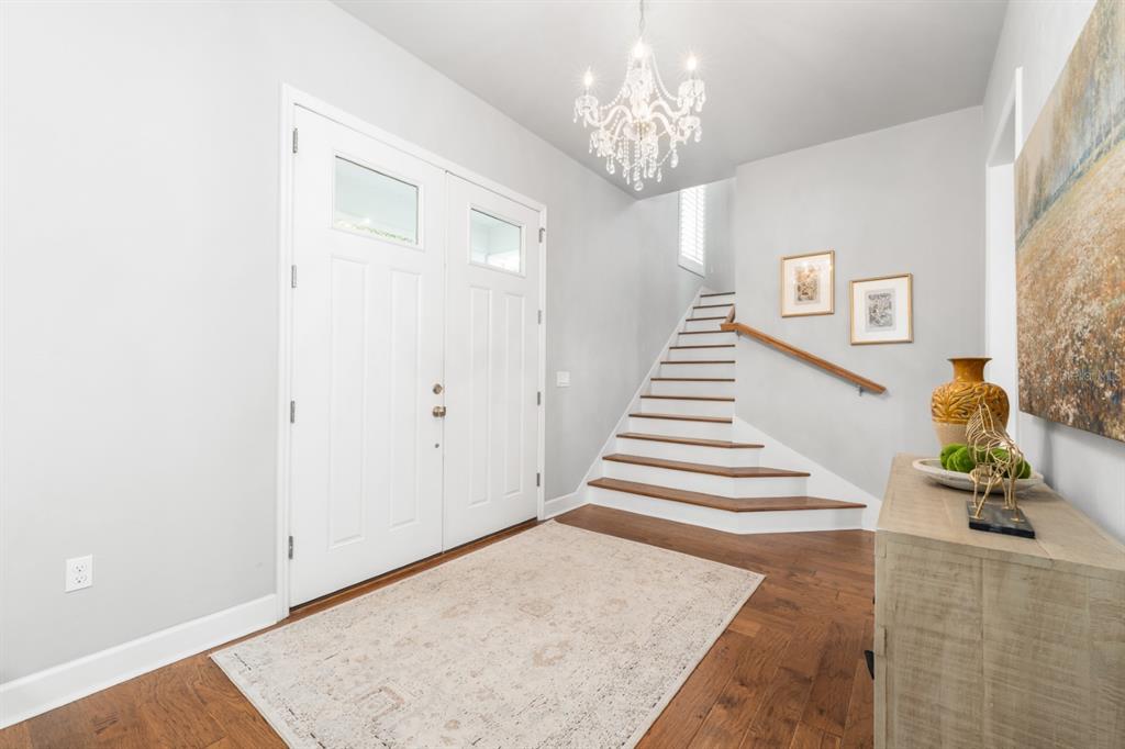 A bright entryway features a double front door, a crystal chandelier, and a wooden staircase — 741 SW 133RD WAY, NEWBERRY, FL