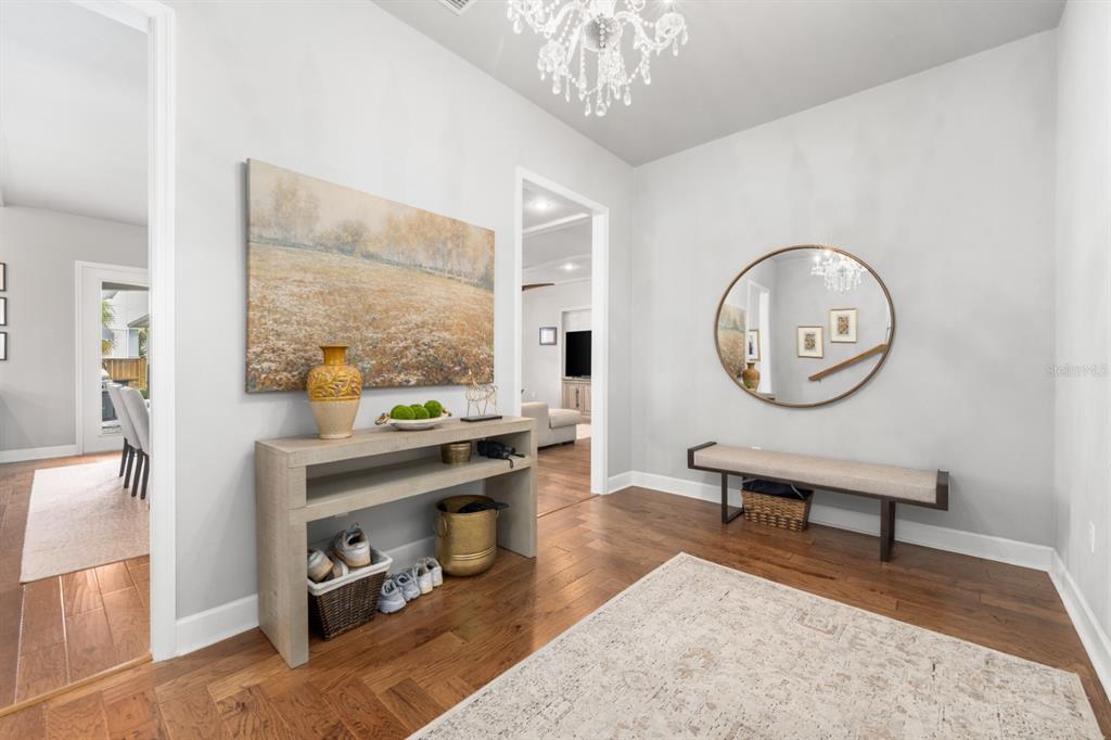 A bright entryway features hardwood floors, a console table, a bench, and a round mirror — 741 SW 133RD WAY, NEWBERRY, FL