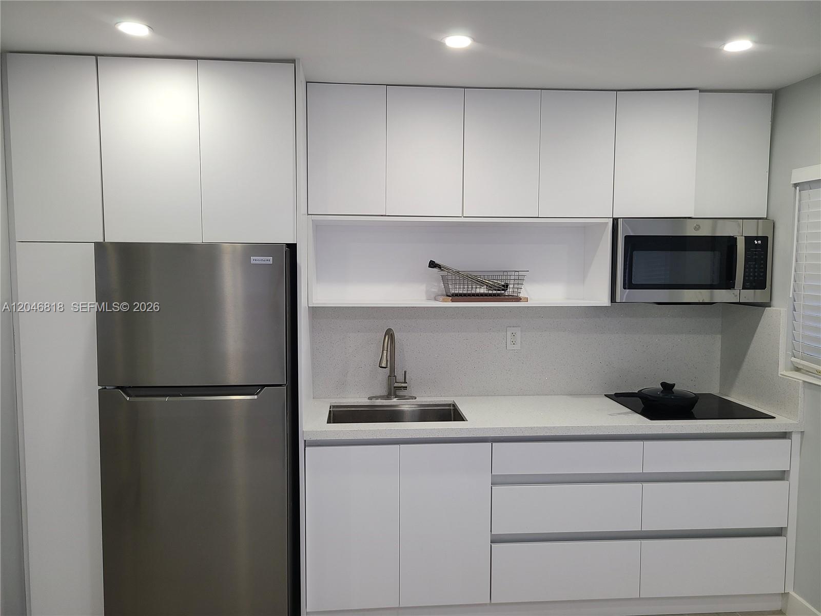 A modern kitchen features white flat-panel cabinetry, stainless steel appliances, and a quartz countertop — 321 Hayes St # 3, Hollywood FL 33019, HOLLYWOOD, FL