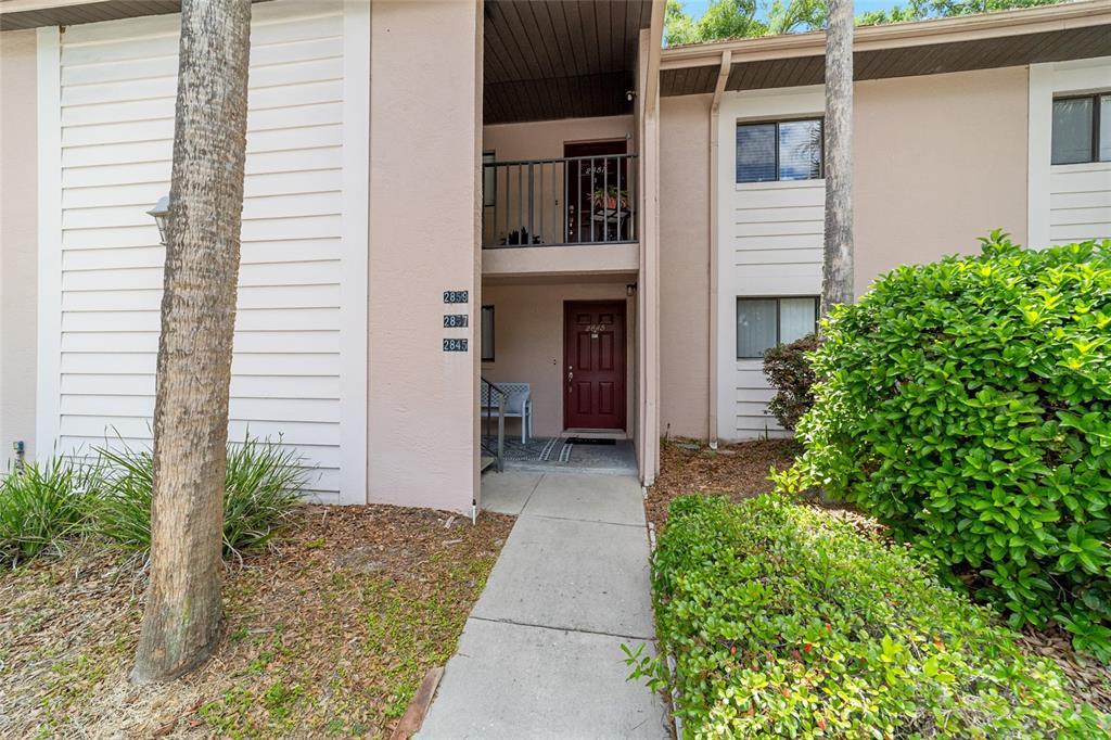 A concrete walkway leads to the entrance of a two-story apartment building with tan siding — 2845 SW 32ND AVENUE UNIT B3, OCALA, FL