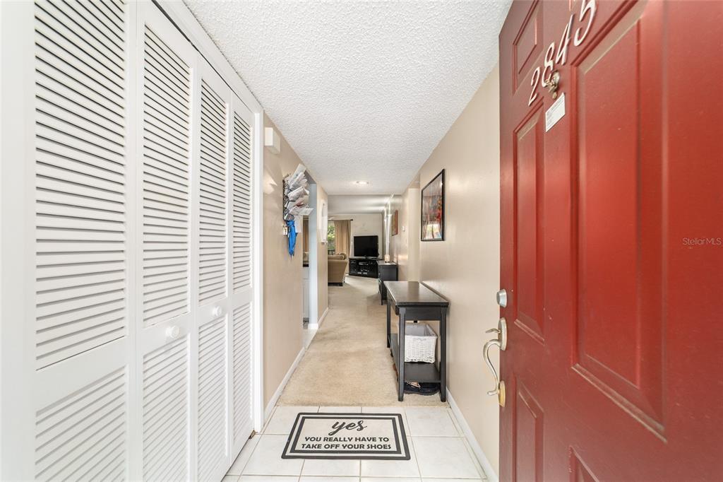 A tiled entryway leads to a carpeted hallway with a red door and louvered closets — 2845 SW 32ND AVENUE UNIT B3, OCALA, FL