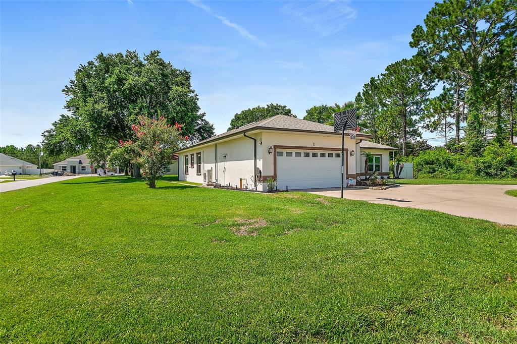 A single-story house with a two-car garage and a basketball hoop in the driveway — 1 SLIPPER FLOWER PATH E, PALM COAST, FL