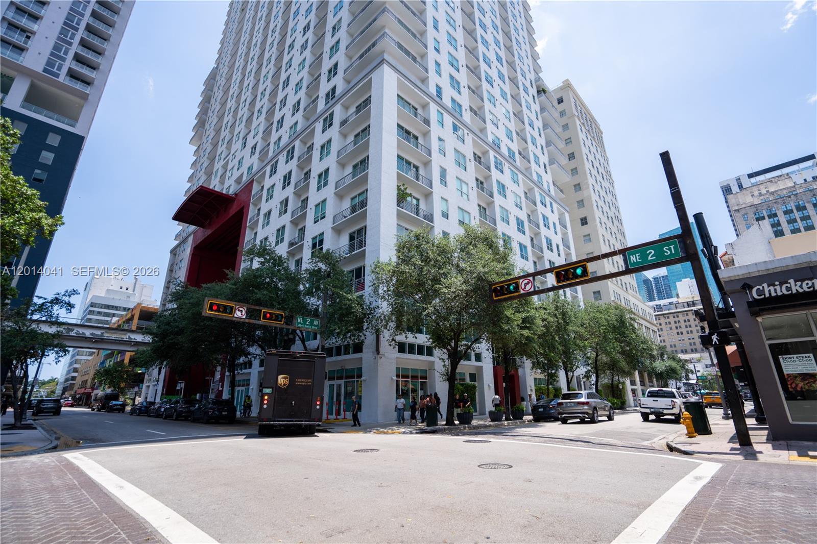 A street-level view shows a tall white apartment building at an urban intersection — 133 NE 2nd Ave # 609, Miami FL 33132, MIAMI, FL