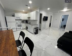 A kitchen with white cabinets and appliances opens into a living area with tiled floors — 2240 Simms St # 3, Hollywood FL 33020, HOLLYWOOD, FL
