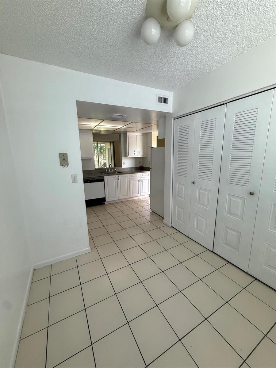 A tiled dining area leads into a kitchen with white cabinets and white appliances — 7895 Margate Boulevard # 203, Margate FL 33063, MARGATE, FL