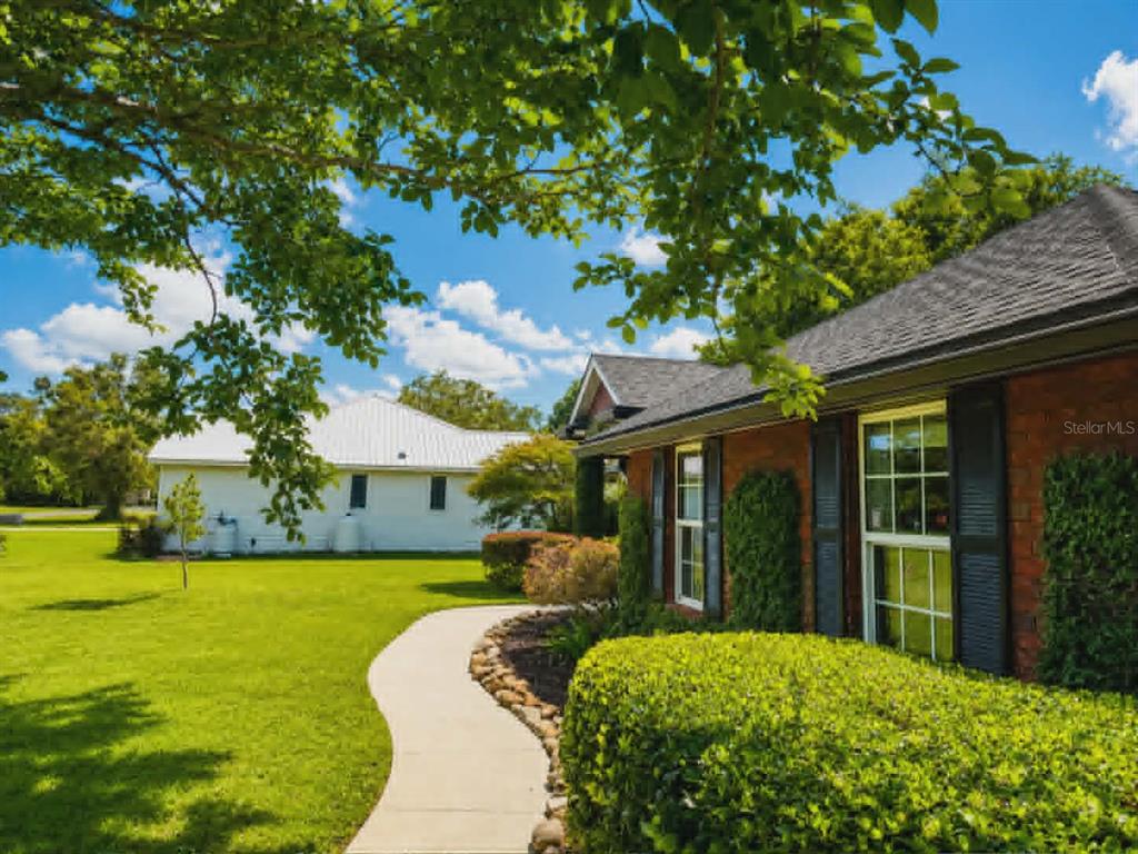 A brick house with dark shutters and a curved walkway sits on a grassy lawn — 96095 GRAVEL CREEK DRIVE, YULEE, FL
