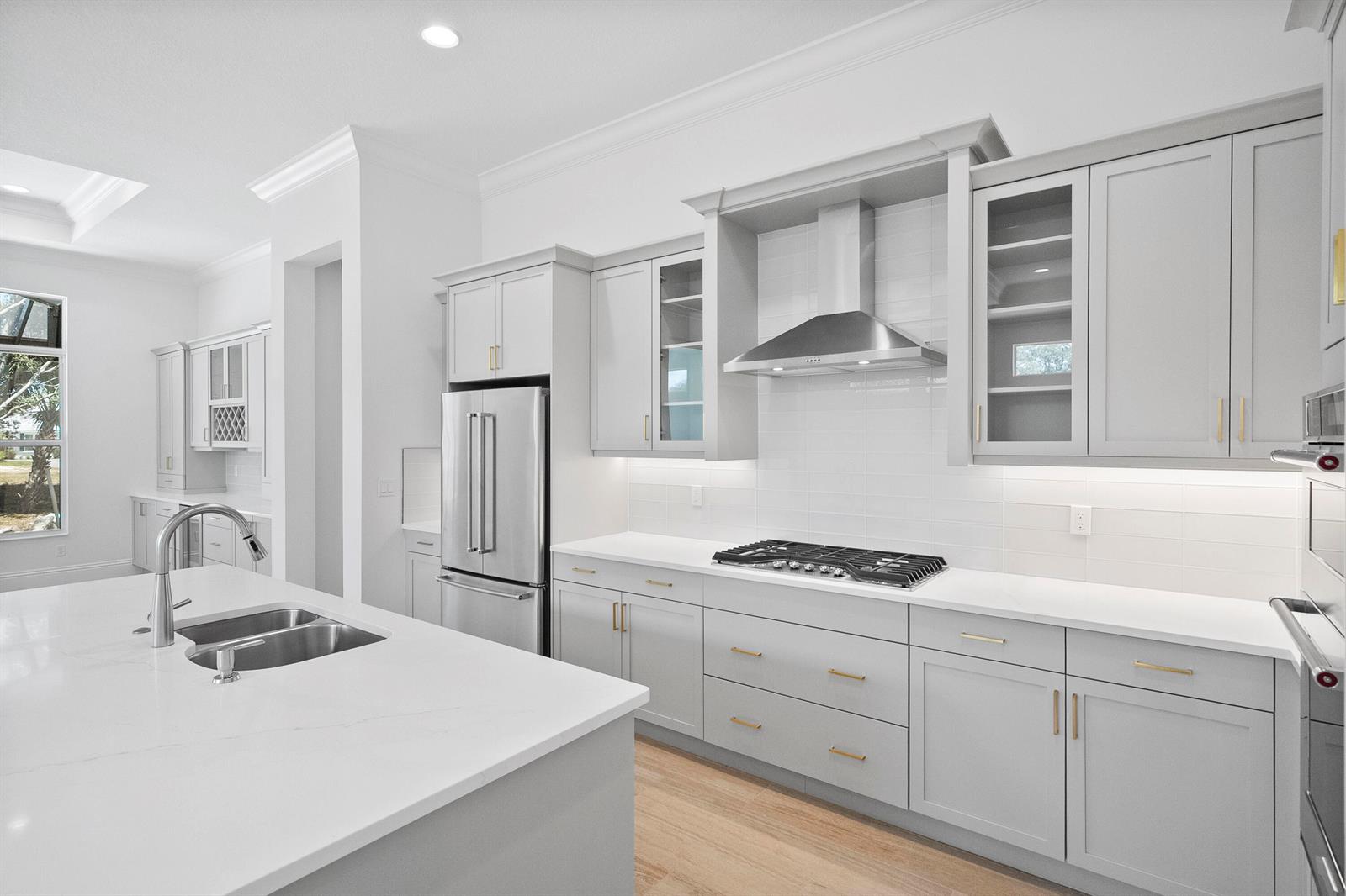 A modern kitchen features light gray cabinetry, white countertops, stainless steel appliances, and an island — 4226 Lucaya Pointe Way, Vero Beach FL 32967, VERO BEACH, FL