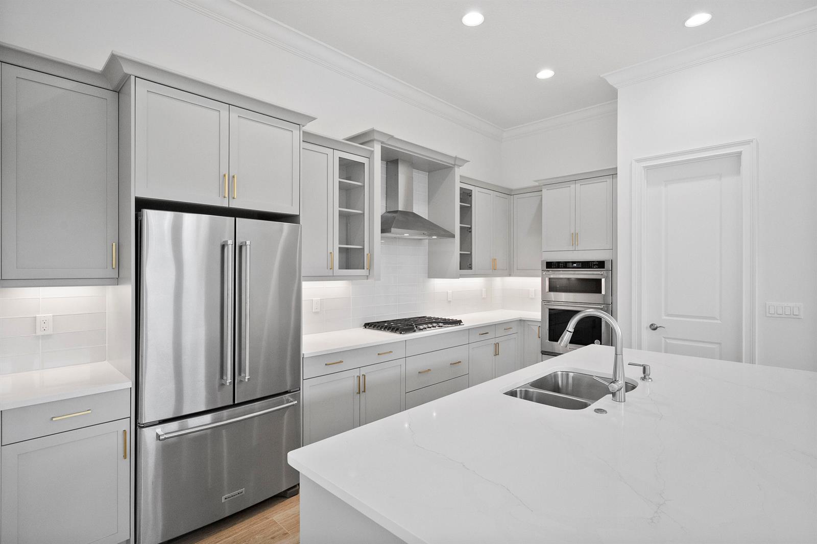 A modern kitchen features light gray cabinetry, stainless steel appliances, and a white quartz island — 4226 Lucaya Pointe Way, Vero Beach FL 32967, VERO BEACH, FL