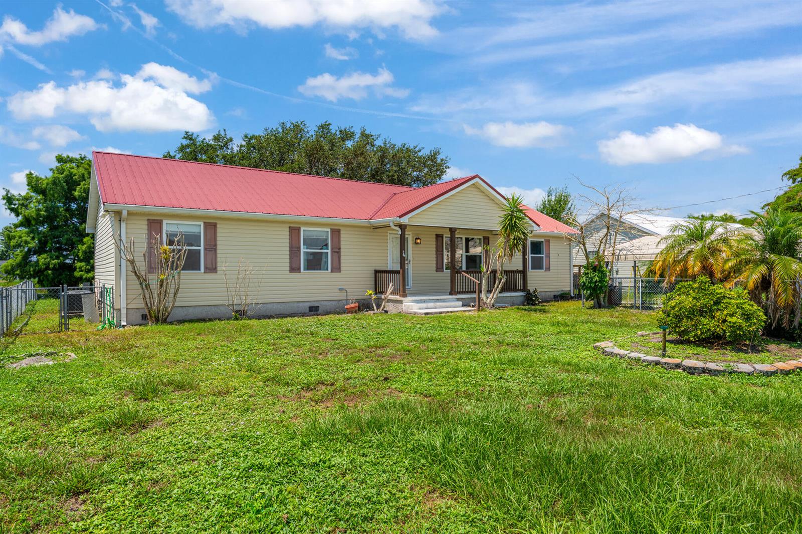 A single-story house with light siding and a red metal roof sits on a lawn — 2546 SE 27th Street, Okeechobee FL 34974, OKEECHOBEE, FL