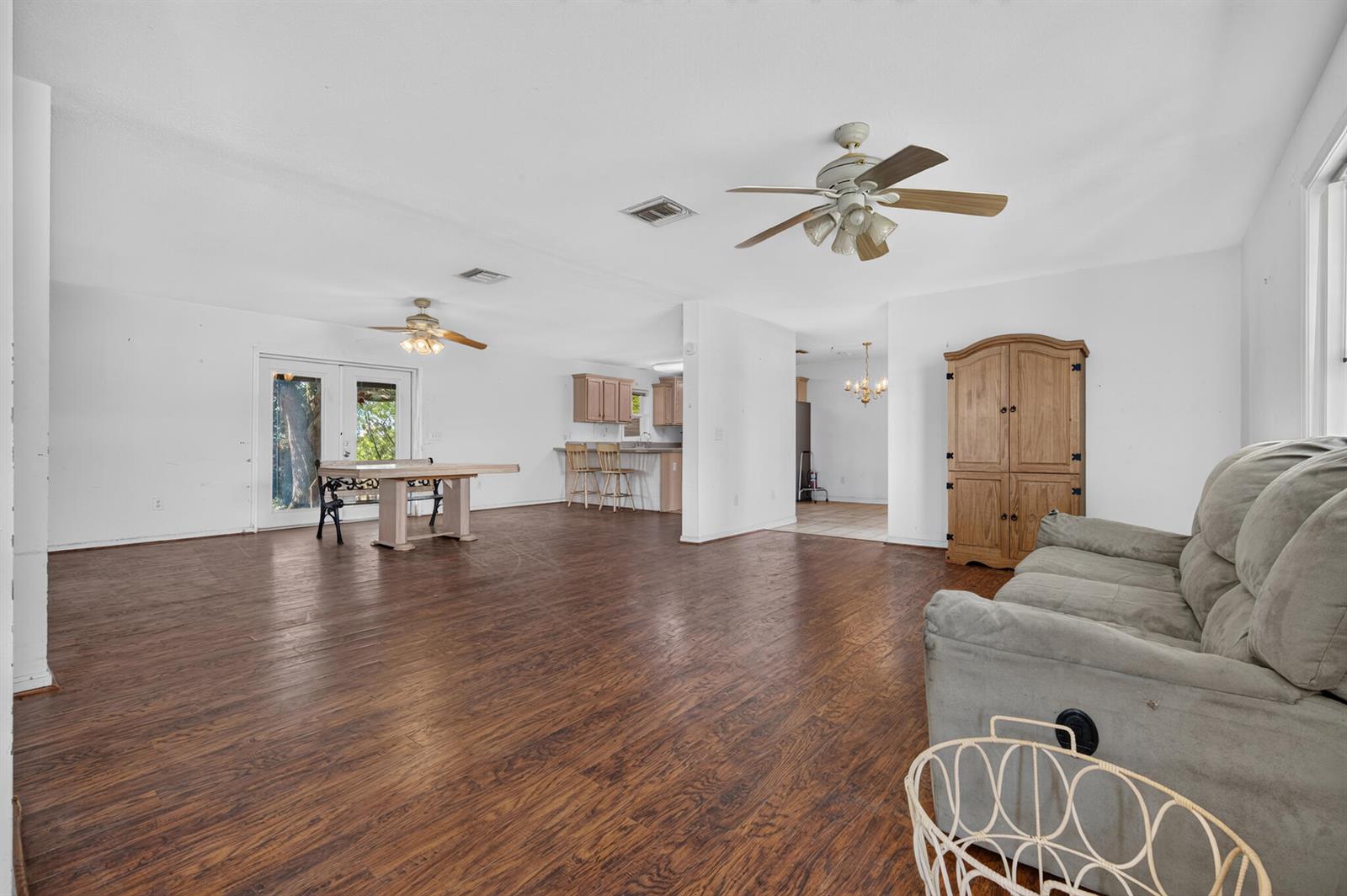 A spacious living and dining area with wood-look flooring, white walls, and two ceiling fans — 2546 SE 27th Street, Okeechobee FL 34974, OKEECHOBEE, FL