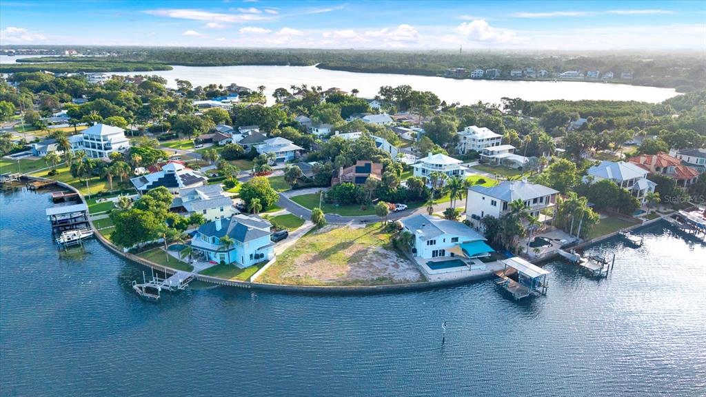 An aerial view shows waterfront houses with private docks along a canal and bay — 121 AUGUSTA AVENUE, PALM HARBOR, FL