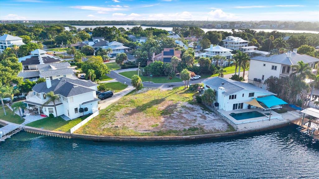 An aerial view shows a vacant waterfront lot situated between two large residential homes — 121 AUGUSTA AVENUE, PALM HARBOR, FL