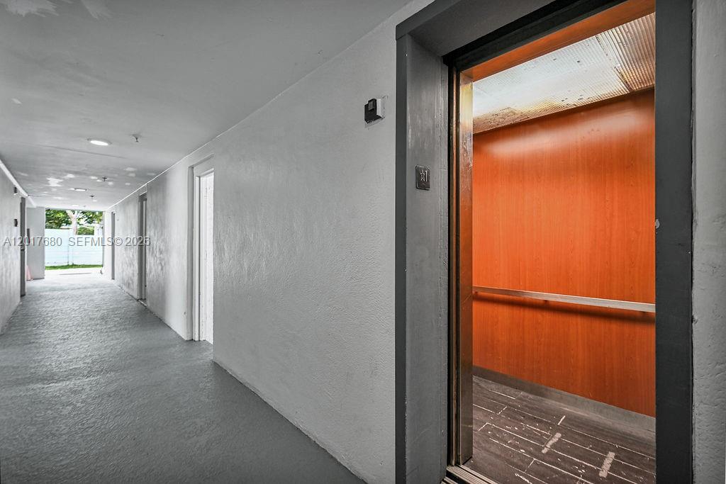 An elevator with wood-paneled walls opens into a long, gray-floored hallway — 2920 SW 28th Ter # 207, Miami FL 33133, MIAMI, FL