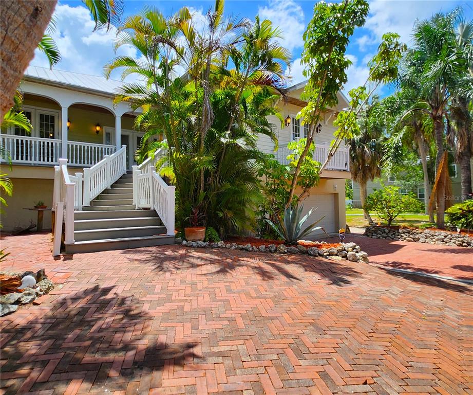 A two-story house with a brick driveway, white railings, and stairs leading to a porch — 102 17TH STREET NE, BRADENTON, FL