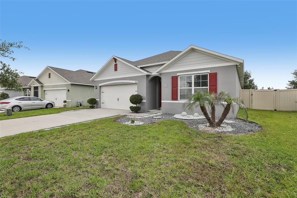 A gray single-story house with a two-car garage, red shutters, and a front lawn — 497 NOBLE AVENUE, DAVENPORT, FL