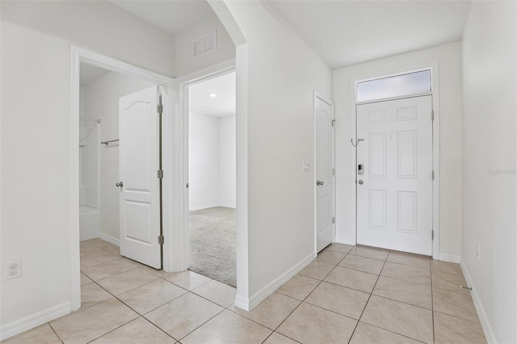 An entryway with tile flooring leads to a carpeted bedroom and a bathroom — 497 NOBLE AVENUE, DAVENPORT, FL