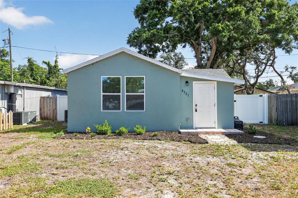 A single-story house with teal siding, a white front door, and a large tree behind it — 4521 41ST AVENUE N, ST PETERSBURG, FL