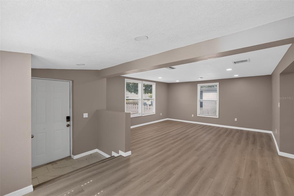 An empty living room features light brown wood-look flooring, taupe walls, and white trim — 4521 41ST AVENUE N, ST PETERSBURG, FL
