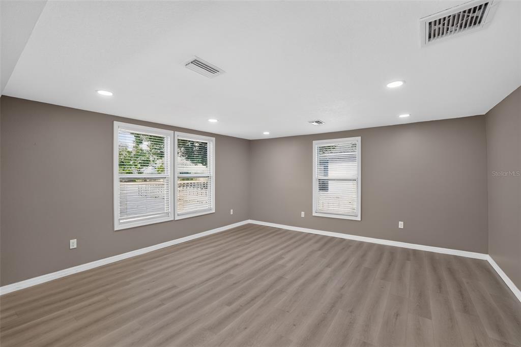 An empty room features gray walls, light wood-look flooring, recessed lighting, and three windows — 4521 41ST AVENUE N, ST PETERSBURG, FL