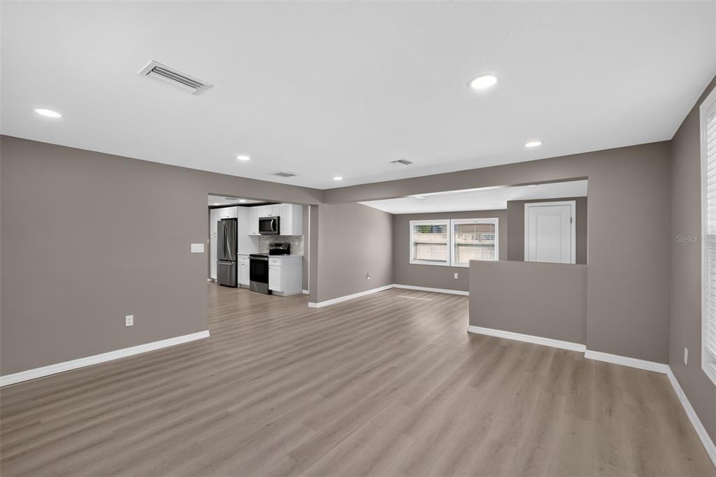 An open-concept living area with gray walls, light wood-look flooring, and a view into the kitchen — 4521 41ST AVENUE N, ST PETERSBURG, FL