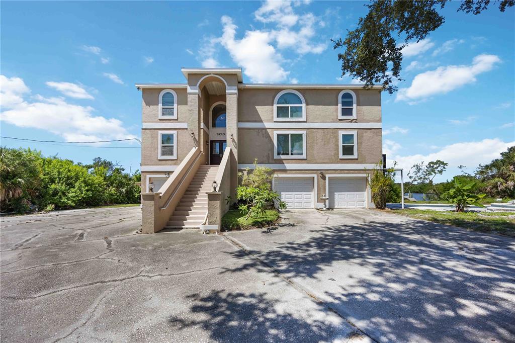 A three-story house with a raised entryway, two garage doors, and a large concrete driveway — 1460 BAYSHORE DRIVE, TERRA CEIA, FL