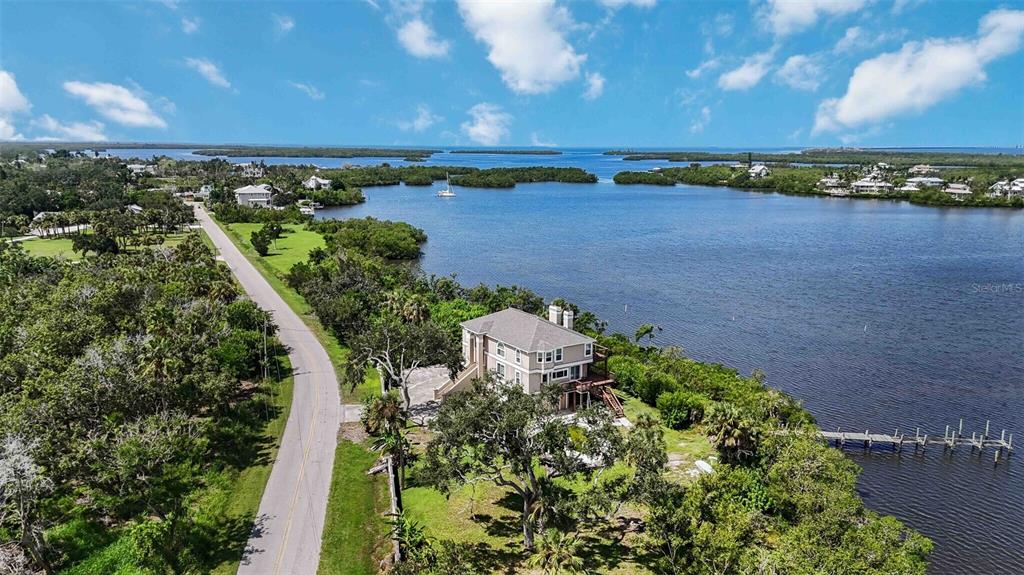 An aerial view shows a house situated on a waterfront lot next to a road — 1460 BAYSHORE DRIVE, TERRA CEIA, FL