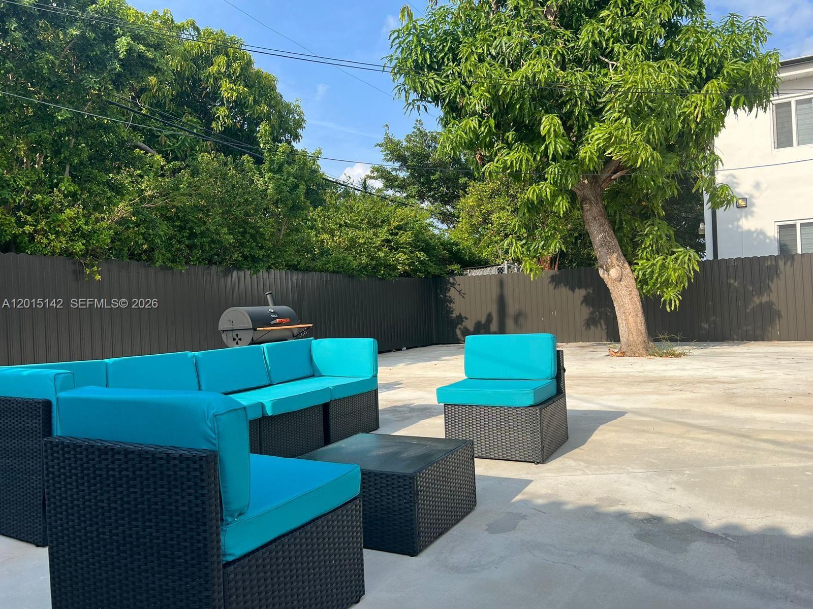 A backyard patio features a modular wicker sofa with turquoise cushions and a charcoal grill — 943 79th Ter # 202, Miami Beach FL 33141, MIAMI BEACH, FL