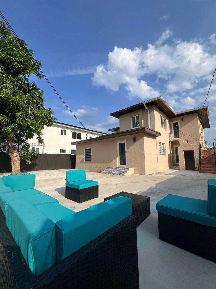 A beige two-story house features a large concrete patio with blue outdoor furniture — 943 79th Ter # 202, Miami Beach FL 33141, MIAMI BEACH, FL
