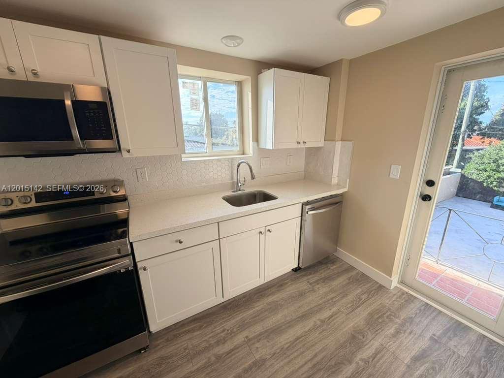 A kitchen features white cabinets, stainless steel appliances, a sink, and light-colored countertops — 943 79th Ter # 202, Miami Beach FL 33141, MIAMI BEACH, FL