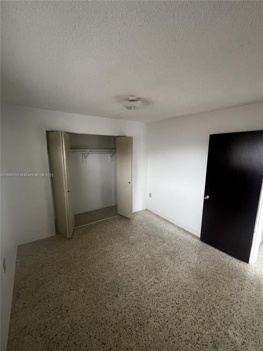 An empty bedroom features white walls, a beige carpet, a closet, and a black door — 619 SW 11th Ave # 2, Miami FL 33130, MIAMI, FL