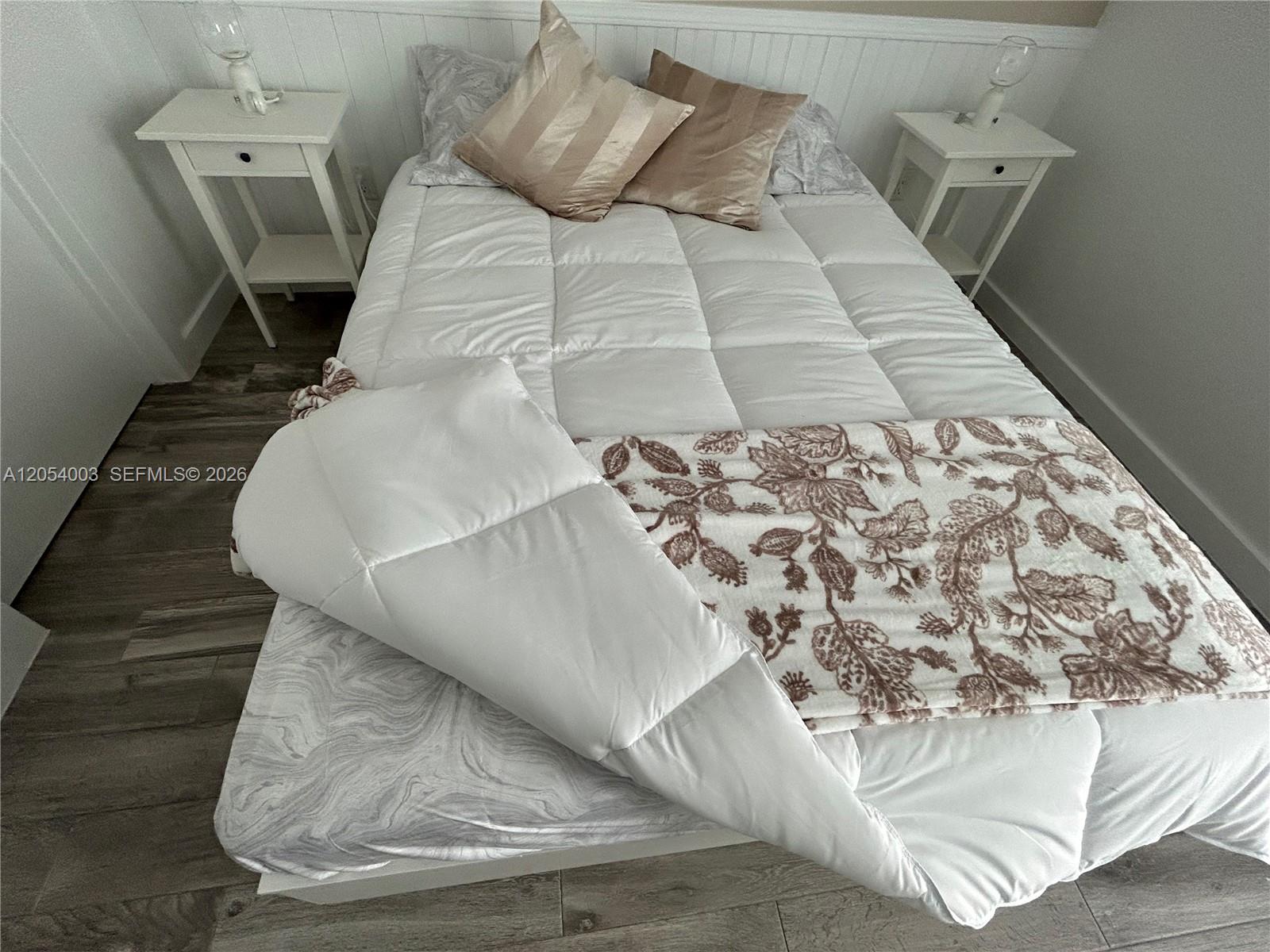 A bedroom features a bed with a white comforter, patterned throw, and two side tables — 1035 Euclid Ave # 27, Miami Beach FL 33139, MIAMI BEACH, FL