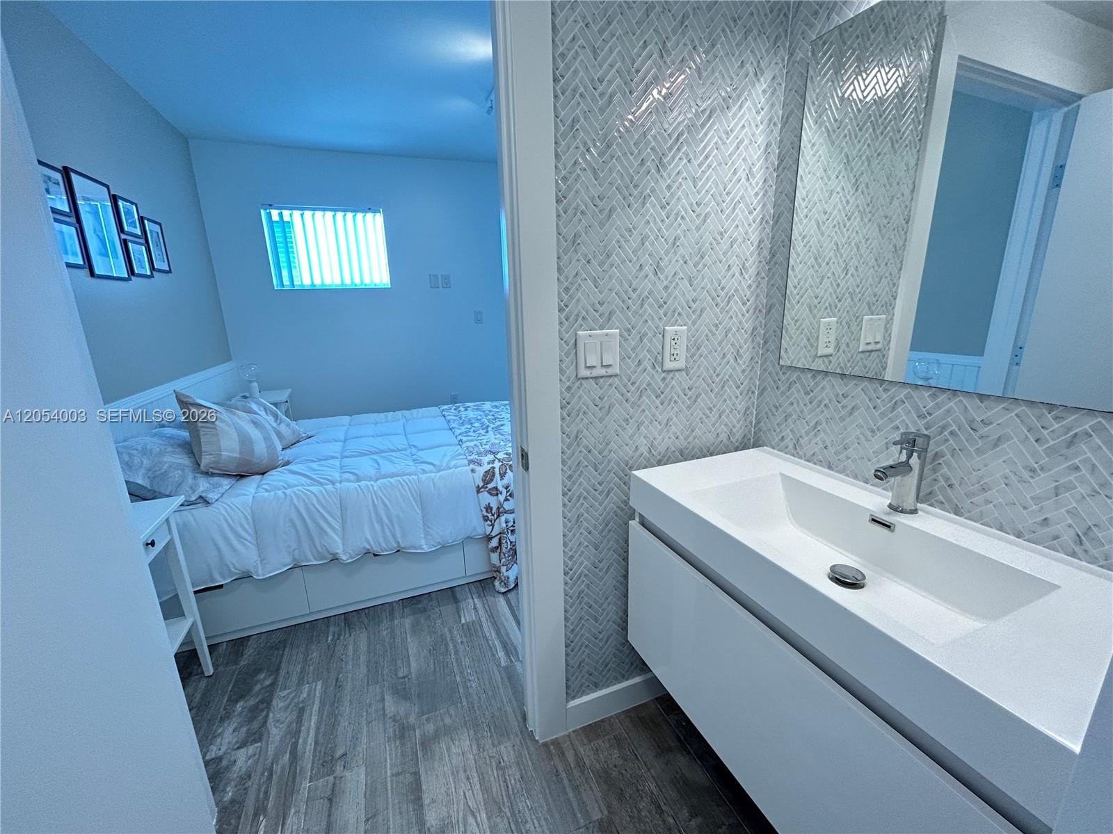 A modern bathroom vanity with a herringbone tile wall opens into a bedroom with flooring — 1035 Euclid Ave # 27, Miami Beach FL 33139, MIAMI BEACH, FL