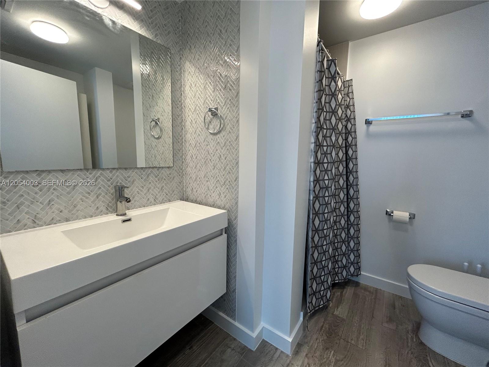 A modern bathroom features a floating vanity, herringbone tile backsplash, and a walk-in shower — 1035 Euclid Ave # 27, Miami Beach FL 33139, MIAMI BEACH, FL